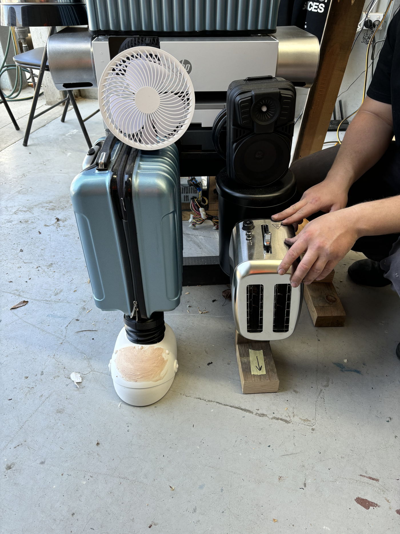 Hands fitting a repurposed toaster into the robot's lower body during assembly