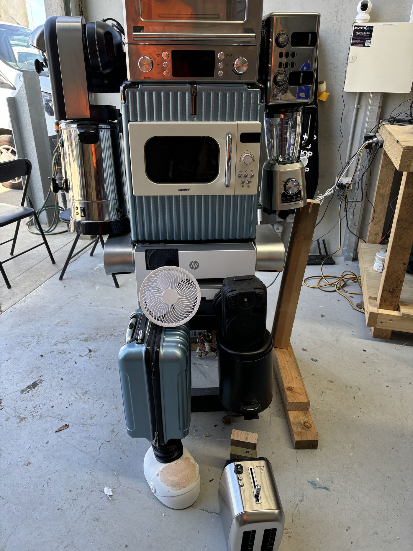 The robot standing part-assembled in the workshop, surrounded by components and timber