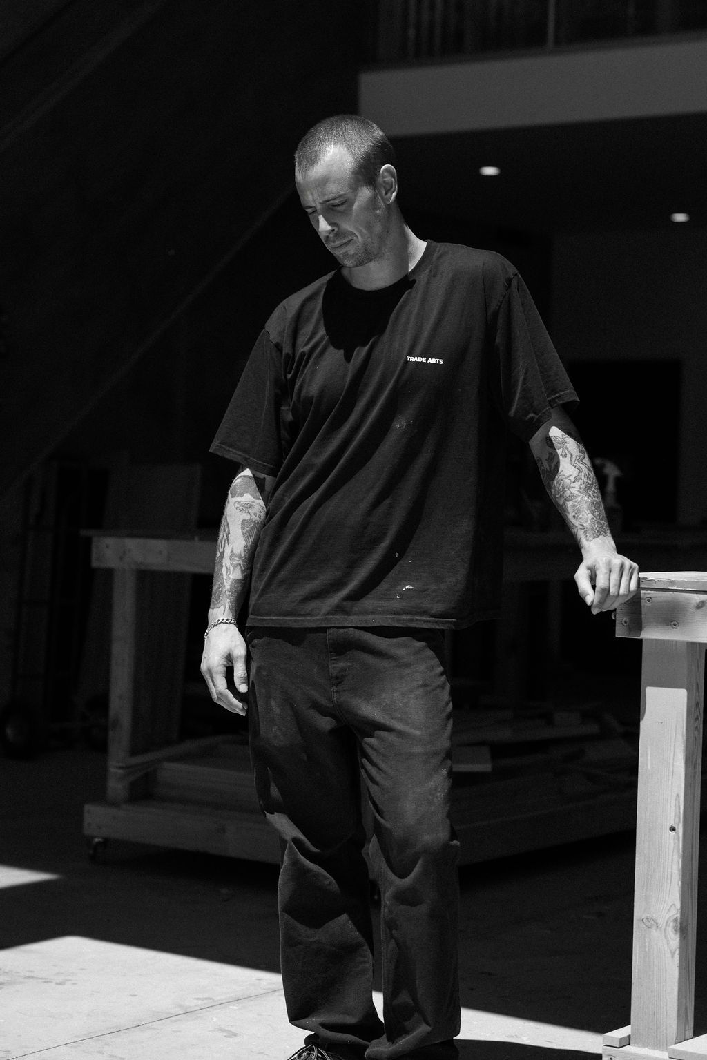 Black-and-white portrait of Bryce Noakes looking away in the Trade Arts workshop