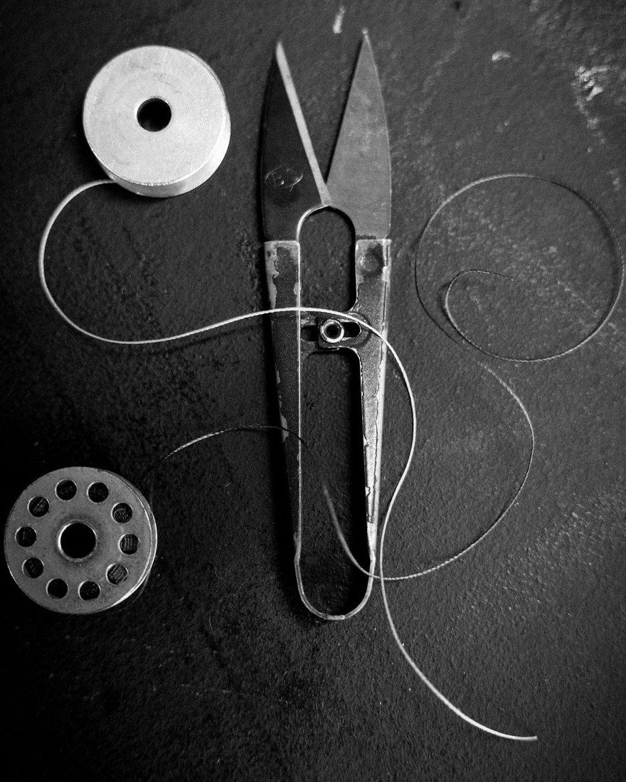 Thread, bobbins and snips laid out on a workbench